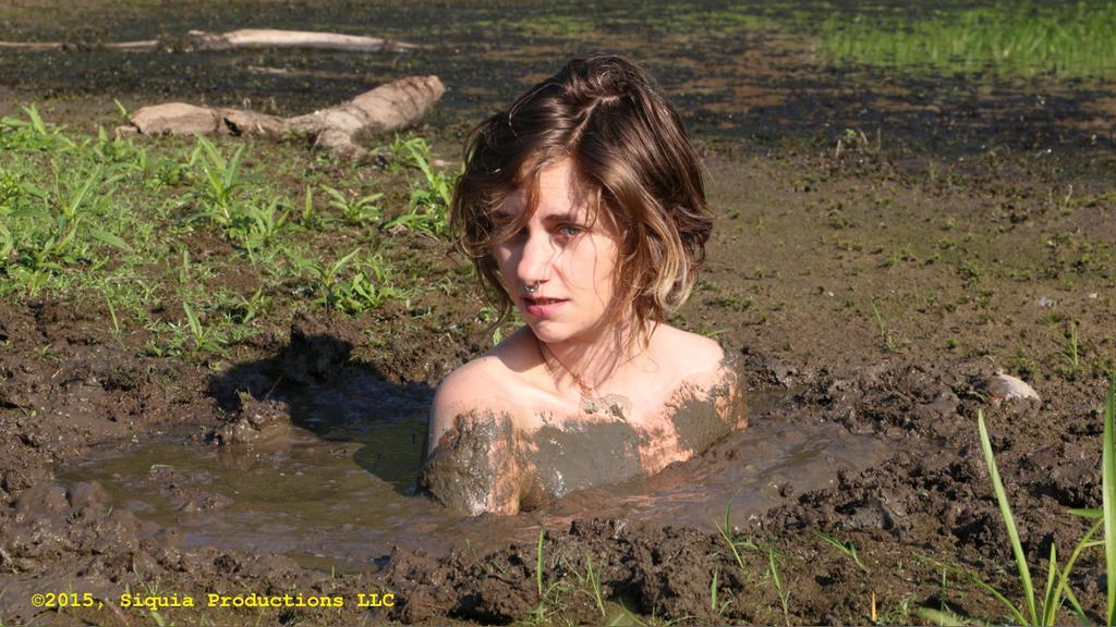 Nude girl swimming in deep mud